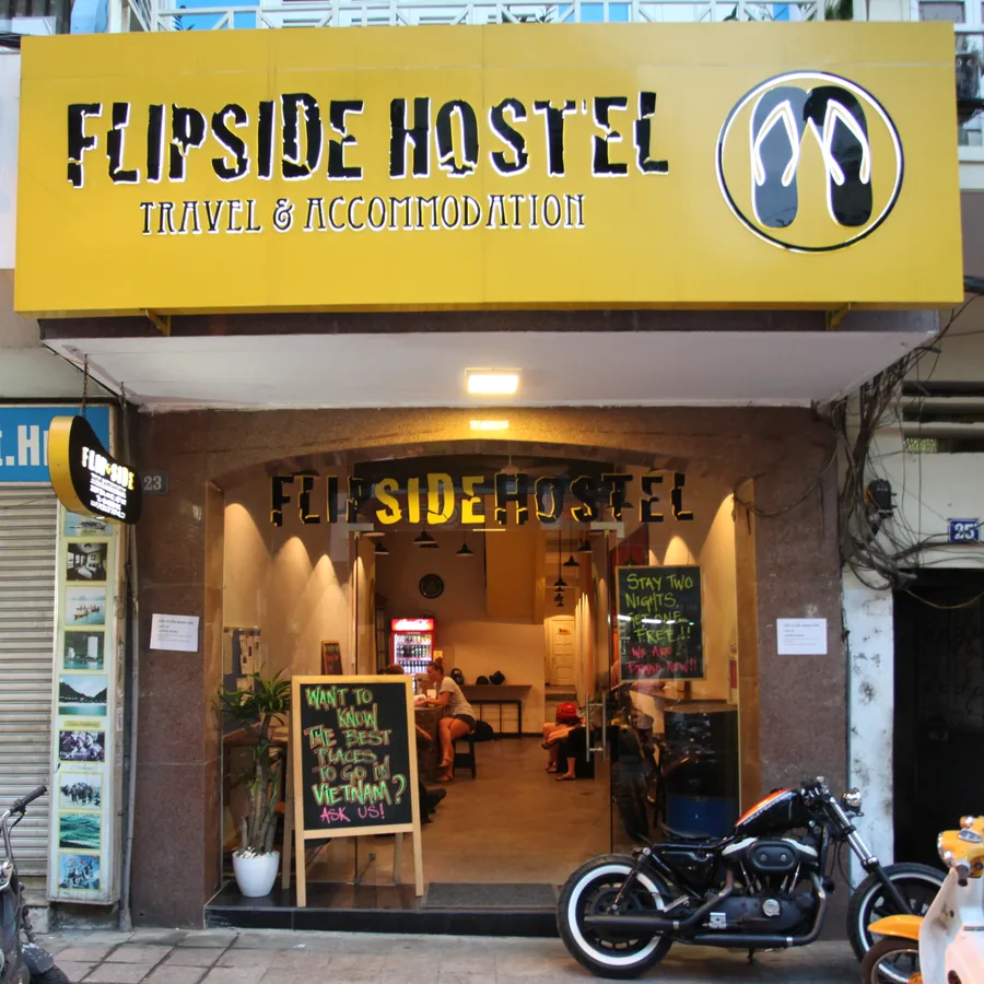 The Flipside Hostel shopfront in Hanoi, yellow sign above an open doorway with a motorbike parked outside