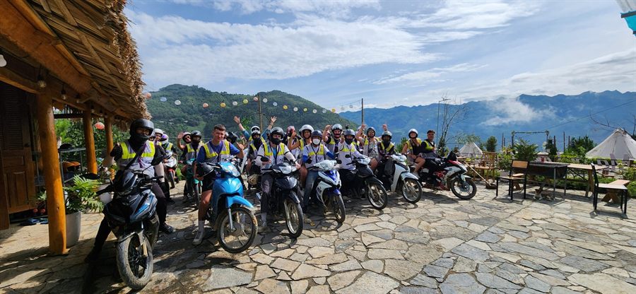 A group of riders waving from a mountain lookout above the valley