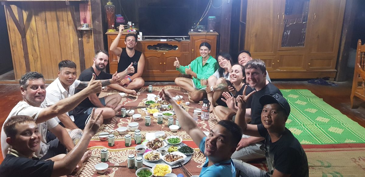 Riders and their hosts sitting on the floor around a spread of dishes
