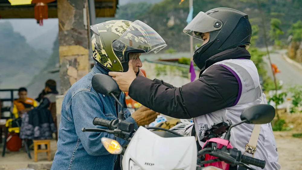 A guide fastening a rider's helmet strap before setting off