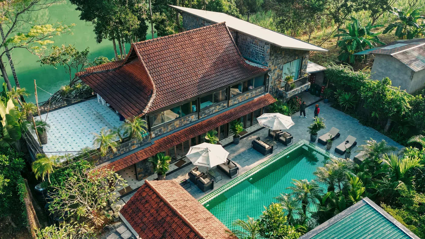 The Flipside Villa in stone and timber, the tiled roof and the hillside behind it