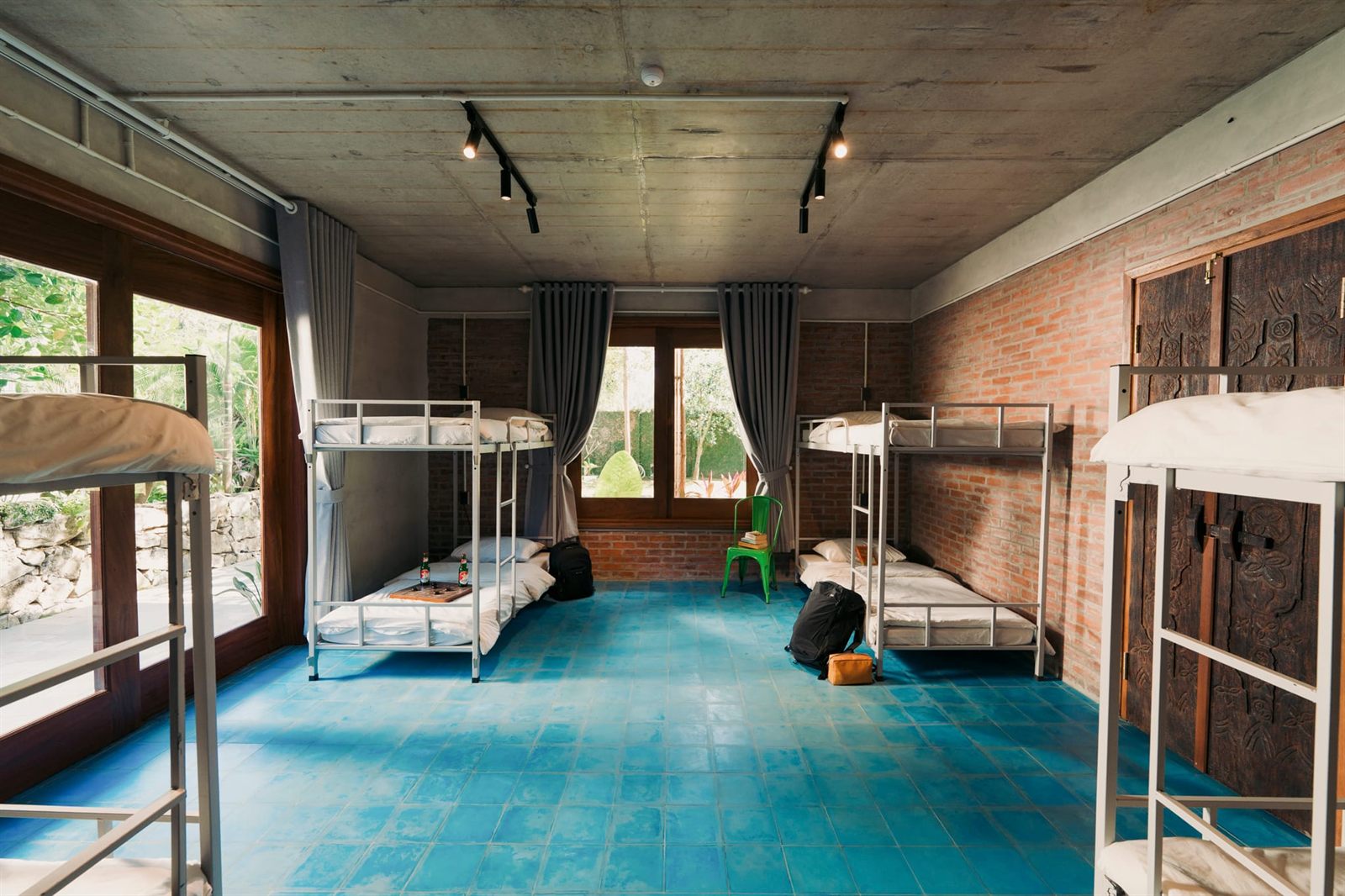 Dorm room with bunk beds along brick walls and a blue tiled floor