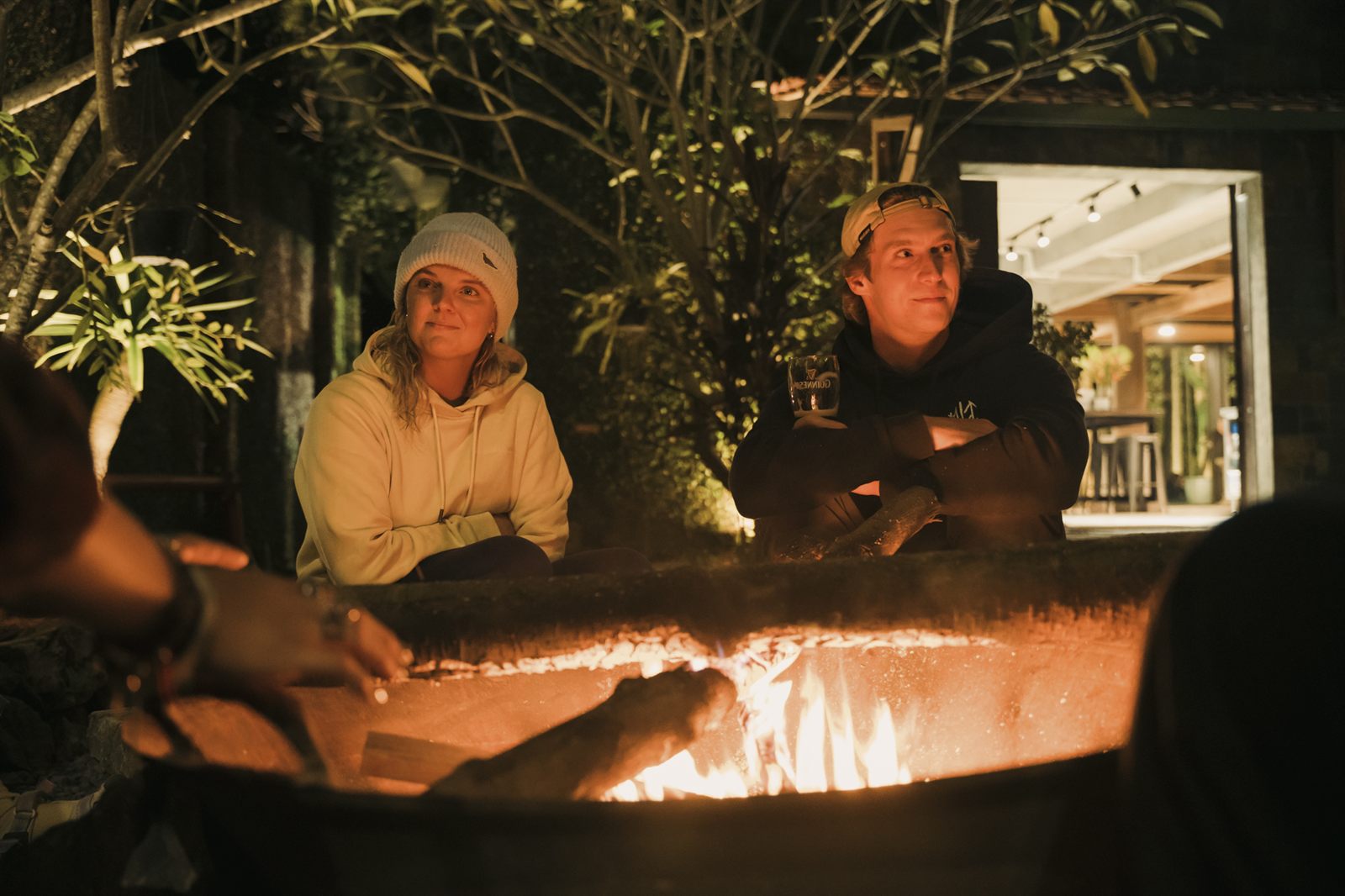 Riders sitting around a lit fire pit at night