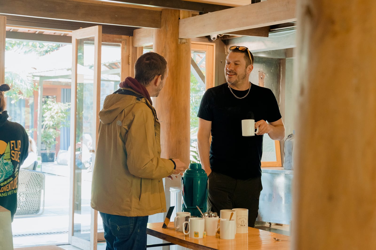 A guide with a coffee behind the bar, talking to a rider before the day starts