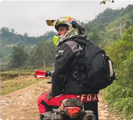 Tom on a loaded bike, looking back down a dirt road