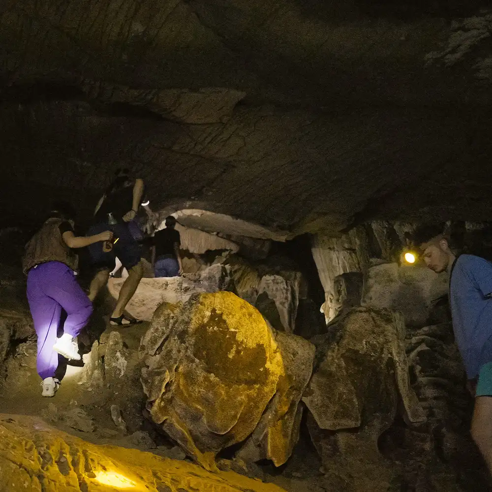 Riders climbing over rocks by torchlight inside a cave on the loop