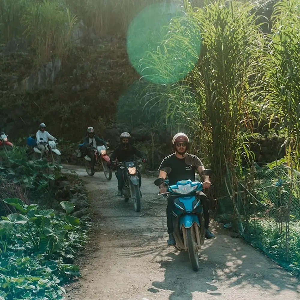 A line of riders on a dirt track through the hills on the Ha Giang Loop