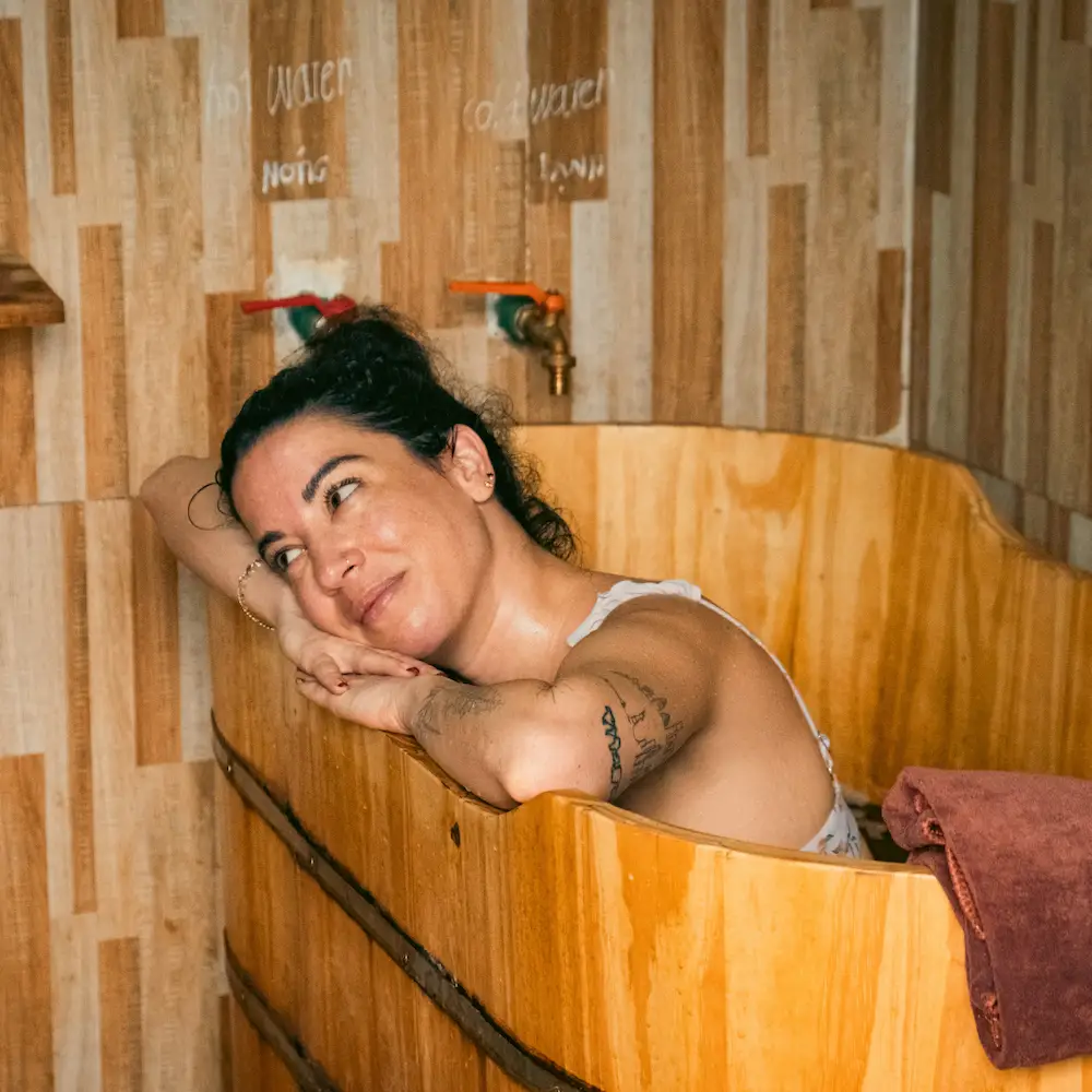 A guest resting in a wooden herbal bath at a homestay