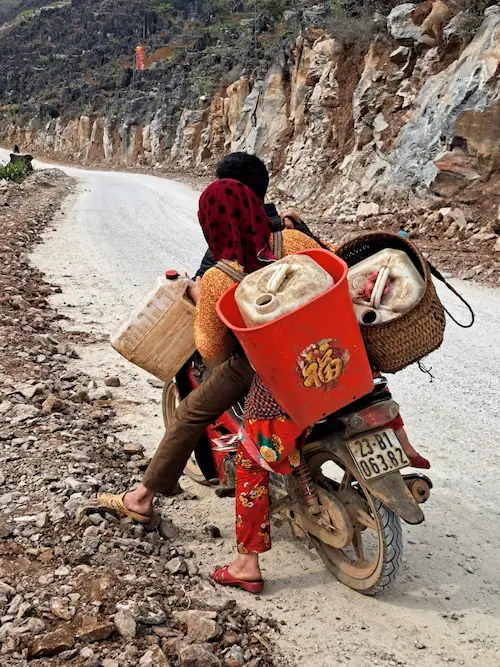 A woman loading baskets onto a motorbike at the roadside