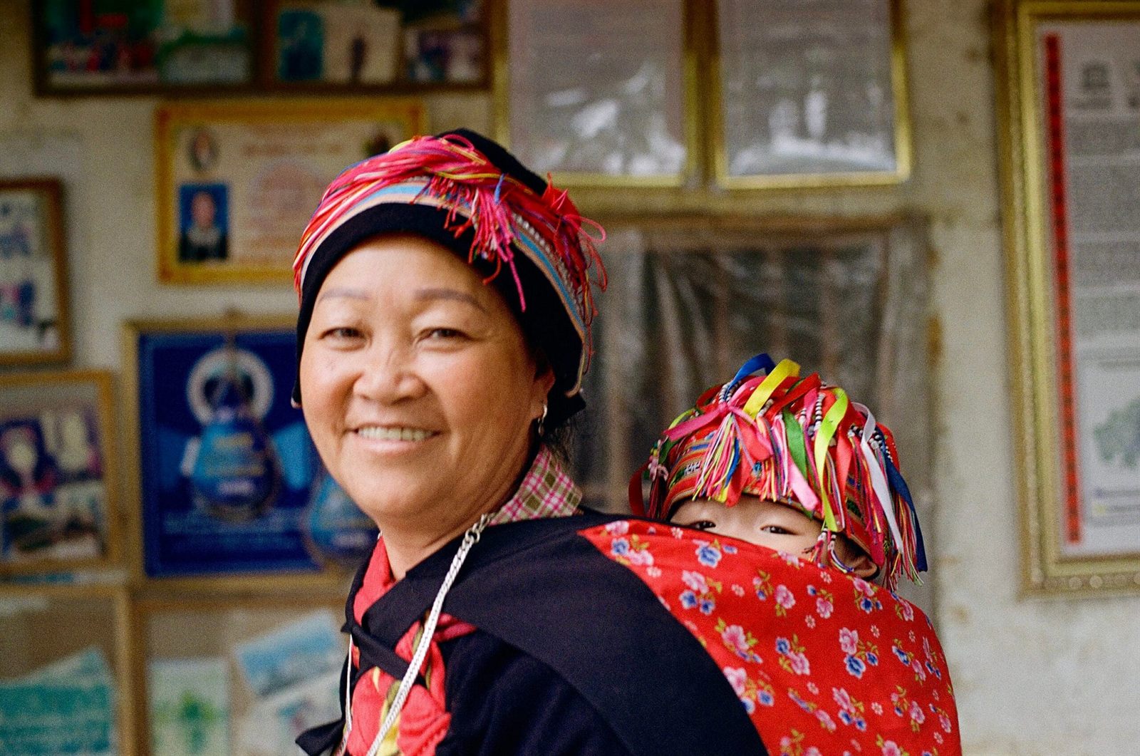 A woman with a baby on her back, both in embroidered dress