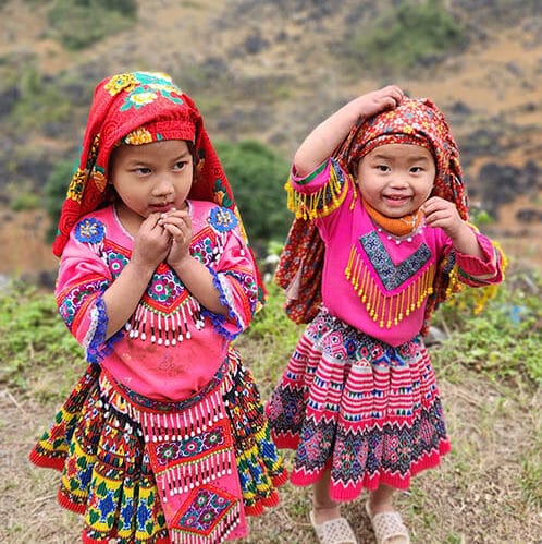 Two young girls in bright traditional dress on a hillside