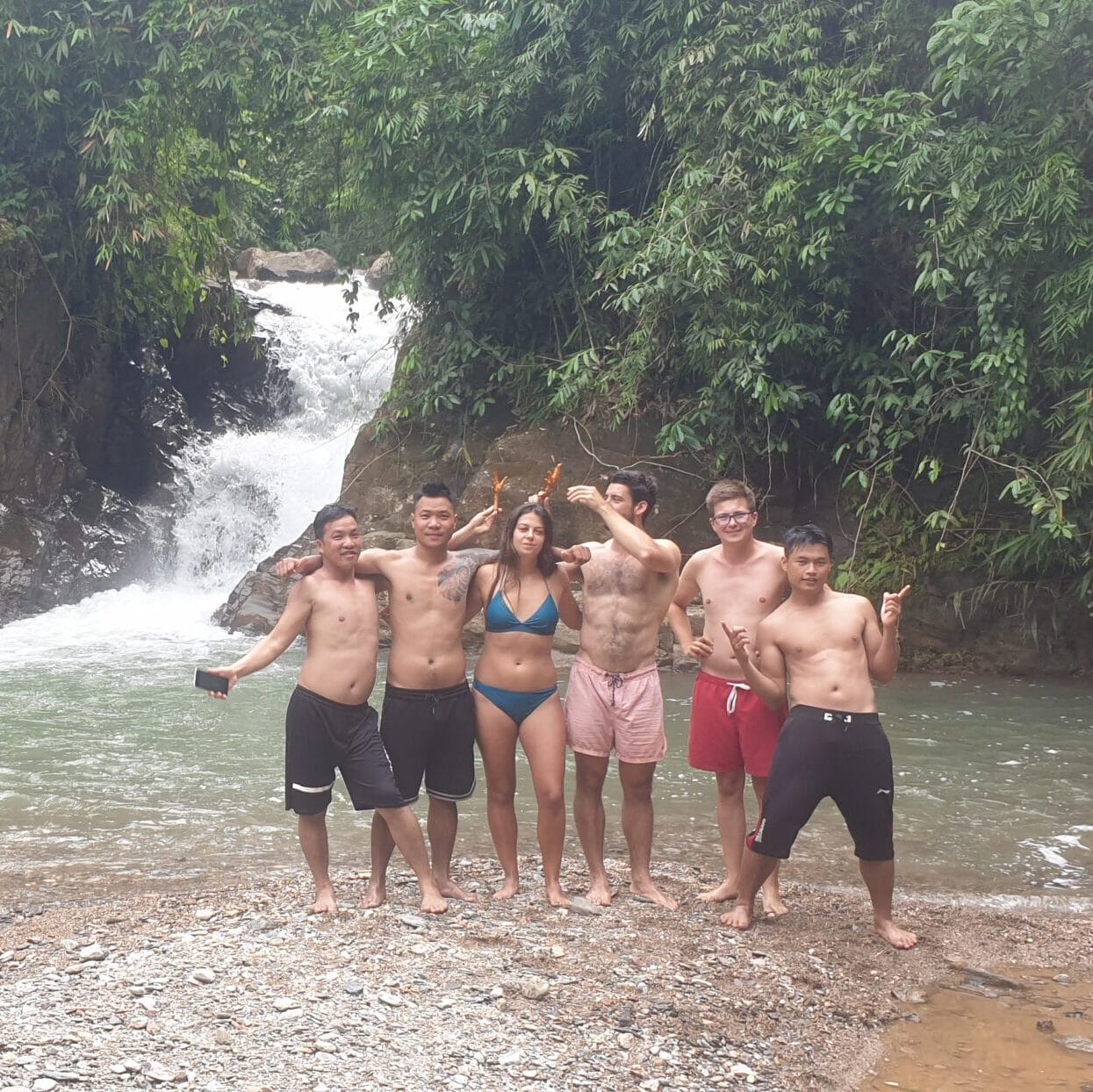 A group posing on the rocks in front of a waterfall