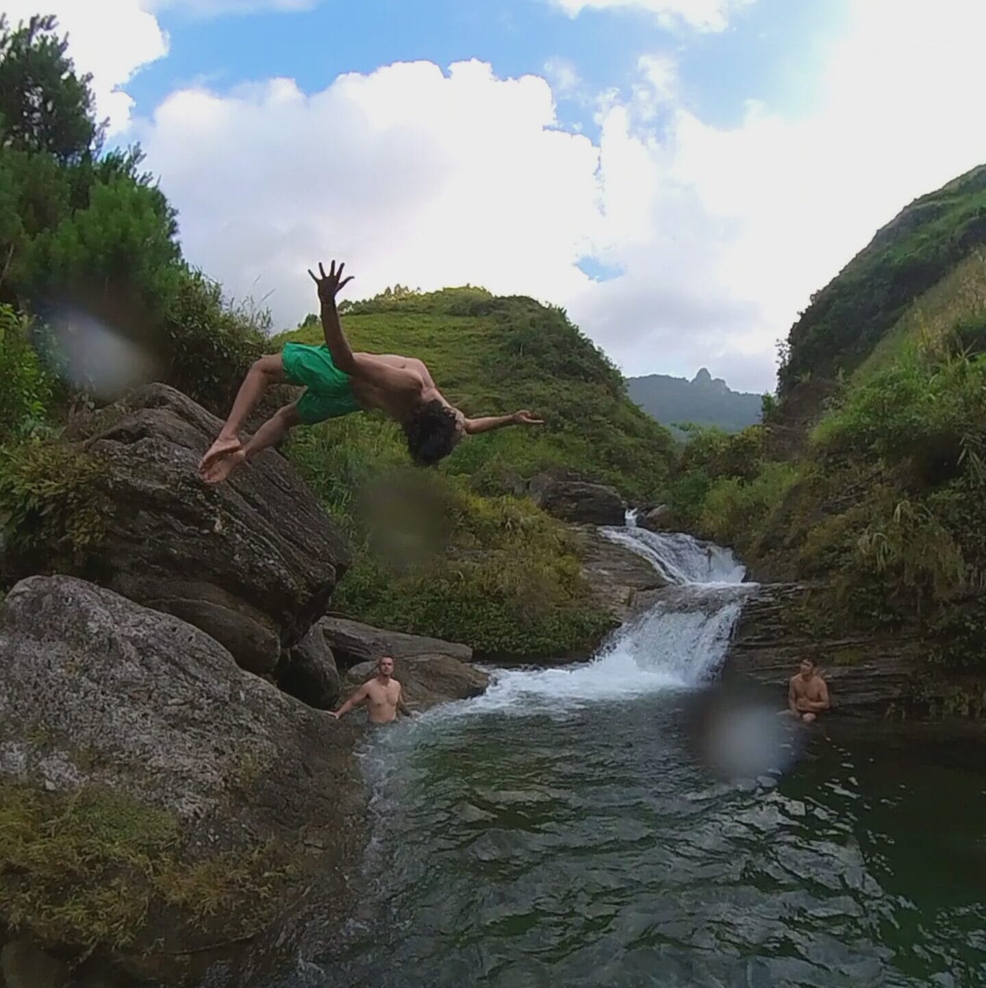 A rider leaping from the rocks into the pool below a waterfall